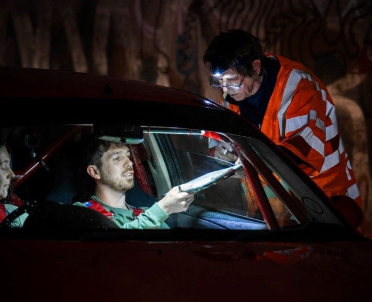 Marshal signing a competitors route check card on a night rally